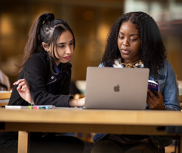 Two diverse female students studying in the library
